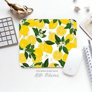 May include: A white mouse pad with a lemon pattern. The pattern features yellow lemons, green leaves, and white flowers. The text "Hello Delicious." is printed on the bottom of the mouse pad.