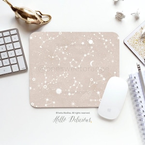 May include: A beige mouse pad with a constellation design featuring white stars, planets, and a crescent moon. The text "@onesweetorange" and "Hello Delicious." is printed on the mouse pad.