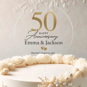 May include: A round, clear acrylic cake topper with gold lettering. The topper says "50 Happy Anniversary Emma & Jackson Married | August 12, 1975".