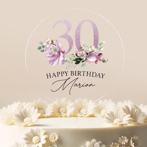 May include: A round cake topper with a floral design and the number 30 in purple. The text "Happy Birthday Marion" is written below the number.