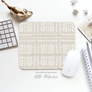 May include: A beige mouse mat with a white geometric pattern. The text "@onesweetorange" is printed on the mouse mat. The mouse mat is on a white surface with a gold metal decorative object, a white computer keyboard, and a white computer mouse.