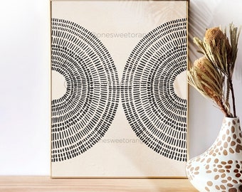 May include: A framed print with a black and white geometric design of two overlapping semi-circles with concentric circles of dots. The print is on a beige background and has a gold frame.