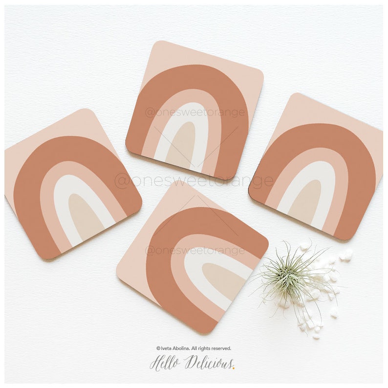 May include: Four square coasters with a rainbow design in shades of brown, pink, and white. The coasters are on a white surface.