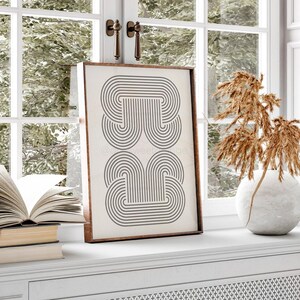 May include: A framed print with a black and white geometric design of overlapping arches. The design is reminiscent of a modern art style.