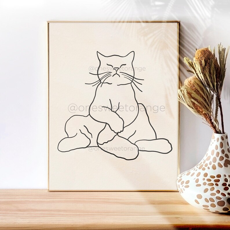 Op de afbeelding: Lijnkunstprint van een kat die in een yogahouding zit. De kat is in zwart getekend op een beige achtergrond. De print is ingelijst in een licht houten lijst.