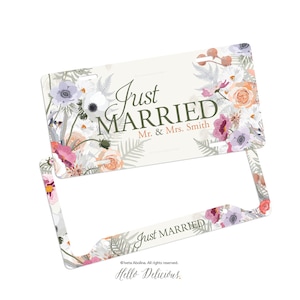 May include: A white license plate frame with a floral design and the text "Just Married" with the names "Mr. & Mrs. Smith".