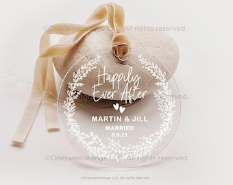 Könnte beinhalten: Ein runder, transparenter Acryl-Anhänger mit einem weißen floralen Kranzdesign und dem Text "Happily Ever After" mit den Namen "Martin & Jill" und dem Datum "9.9.21".