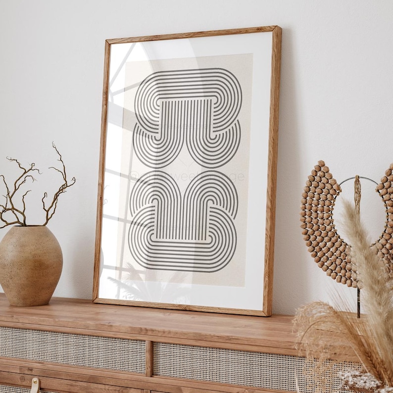 May include: A framed print with a black and white geometric design of overlapping arches. The print is on a cream background and is framed in a natural wood frame.