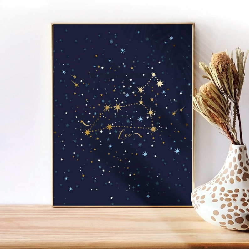 May include: A navy blue poster with a gold constellation of Leo, surrounded by white and blue stars. The word "Leo" is written in gold cursive script.
