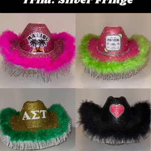 Peut inclure: Quatre chapeaux de cow-boy avec une bordure en franges argent&eacute;es. Les chapeaux sont d&eacute;cor&eacute;s de paillettes et de diff&eacute;rents motifs, dont les mots "Malibu", "Patron", "AZT" et un c&oelig;ur rose.