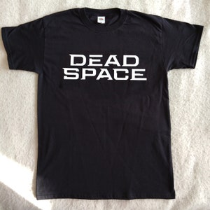 Könnte beinhalten: Schwarzes T-Shirt mit weißem Text, der "DEAD SPACE" lautet.