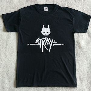 May include: Black t-shirt featuring a white graphic of a cat and the word "Stray" in a stylised font.