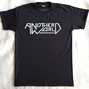 Könnte beinhalten: Schwarzes T-Shirt mit einem weißen Aufdruck des Textes "ANOTHER WORLD" in einer stilisierten Schrift.