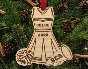 May include: Wooden Christmas bauble shaped like a cheerleader outfit with a pom-pom and megaphone. The bauble is personalised with the name "CHLOE" and the year "2022".