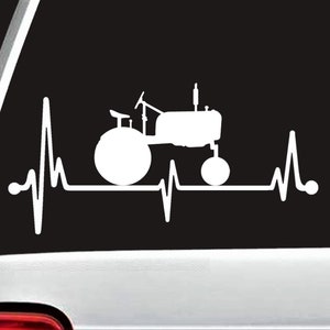 May include: White silhouette of a tractor with a heartbeat graphic. The tractor is facing right and has a large front tire. The heartbeat graphic is behind the tractor and has a white outline.