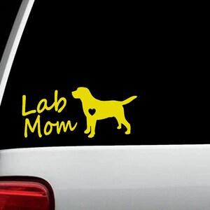 May include: Yellow vinyl decal with a silhouette of a Labrador Retriever with a heart on its chest and the text "Lab Mom" in a handwritten font.