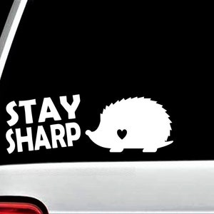 May include: White vinyl decal with the text "Stay Sharp" and a silhouette of a hedgehog with a heart on its chest.