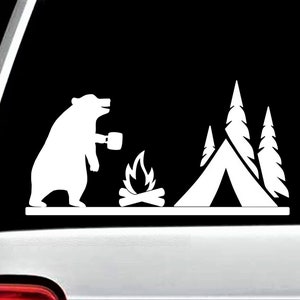May include: A white silhouette of a bear holding a mug, sitting by a campfire with a tent and trees in the background.