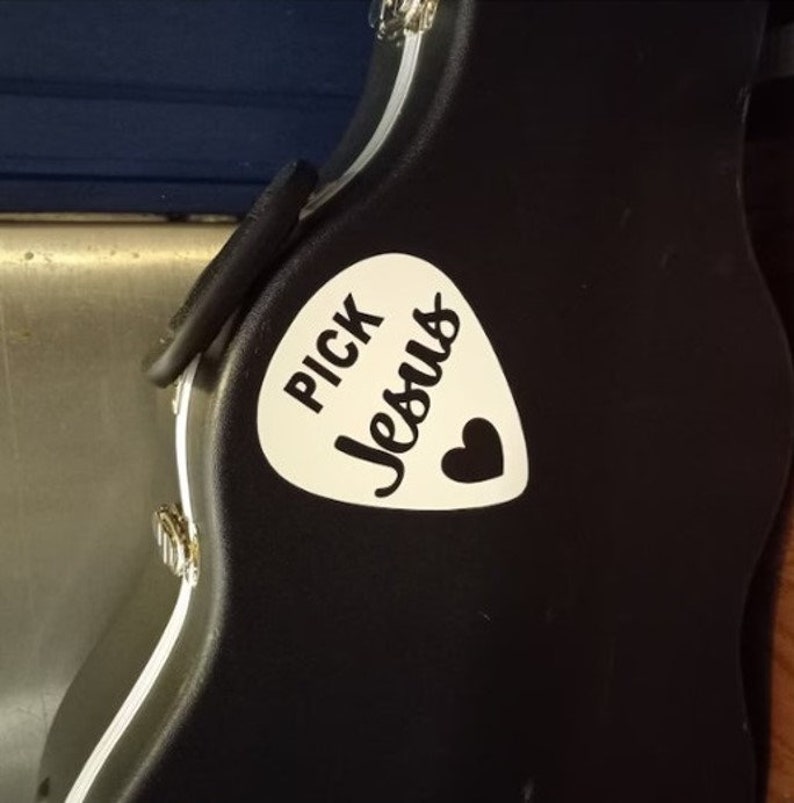May include: A black guitar case with a white pick-shaped sticker that says "Pick Jesus" with a small heart.