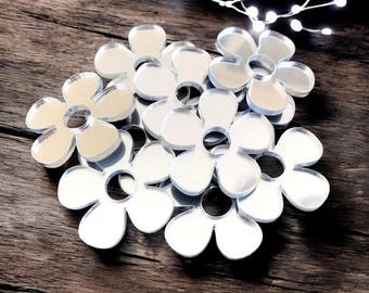 May include: A group of silver mirrored flower-shaped decorations. The flowers have six petals and a center hole.