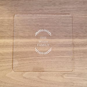 Può includere: Un vassoio da portata quadrato in acrilico trasparente con il testo "THE Willow FAMILY" inciso in un design a corona.