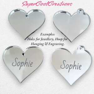 May include: Four silver mirror heart-shaped acrylic blanks with holes for hanging or jewelry making. The blanks are shown with the text "Sophie" engraved on two of them. The text "Examples: Holes for Jewellery, Hoop for Hanging & Engraving" is also shown.