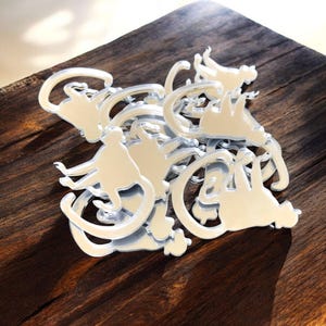 Puede incluir: Un montón de recortes de monos de espejo plateado. Los monos están en varias poses, algunos sentados, algunos de pie y algunos columpiándose de una rama.