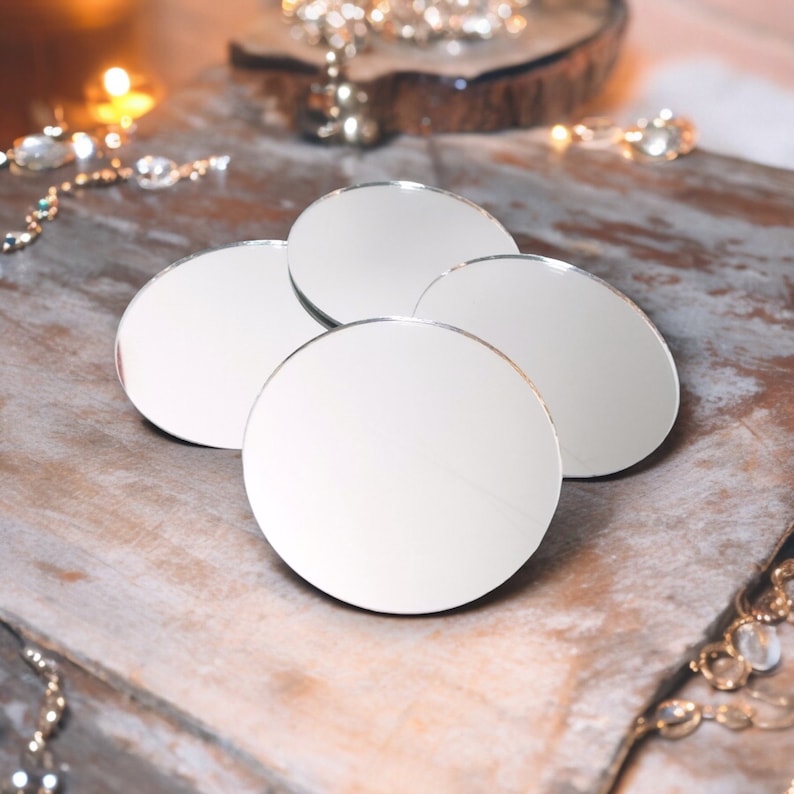 May include: Four round, silver-rimmed, decorative mirrors on a wooden surface. The mirrors are arranged in a semi-circle.