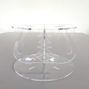 Puede incluir: Soporte para pastel de acrílico transparente con base redonda y diseño decorativo. El soporte tiene un diseño de varios niveles con un nivel superior y un nivel inferior.