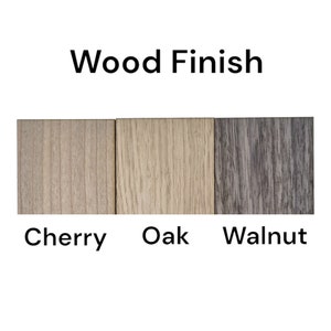 May include: Image showing three wood finish samples: Cherry, Oak, and Walnut. The text "Wood Finish" is above the samples. The Cherry sample is light brown, the Oak sample is beige, and the Walnut sample is gray.