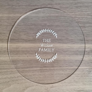 May include: A clear round acrylic serving tray with the text "THE Willow FAMILY" engraved in white lettering surrounded by a wreath of leaves.