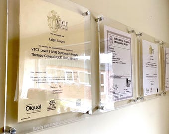 May include: A framed certificate with a gold seal and the text "VTCT World Class Qualifications" and "Leigh Sinden" is displayed on a wall. The certificate is for a VTCT Level 3 NVQ Diploma in Beauty Therapy General (QCF) (500/8860/9).