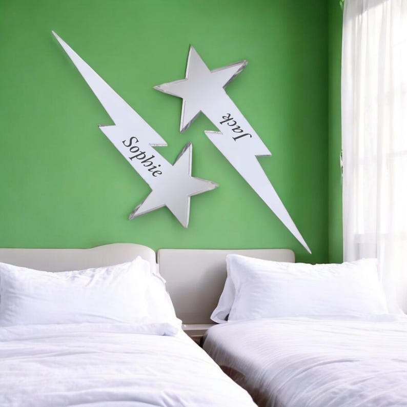 May include: Two white lightning bolt shaped mirrors with star tips, each with a name on them, "Jack" and "Sophie", mounted on a green wall above two white twin beds.