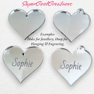 May include: Four silver mirror heart-shaped ornaments. Two of the hearts have the name "Sophie" engraved on them. The text "Examples: Holes for Jewellery, Hoop for Hanging & Engraving." is printed below the ornaments.