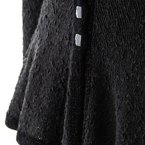 May include: Black knitted dress with a ruffled hem and white buttons down the front.
