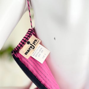 May include: Pink and black striped dress with a black zipper and a white tag that reads "mara jrs. of california" with the text "machine wash warm" and "style 2905 cut 188 size 7"