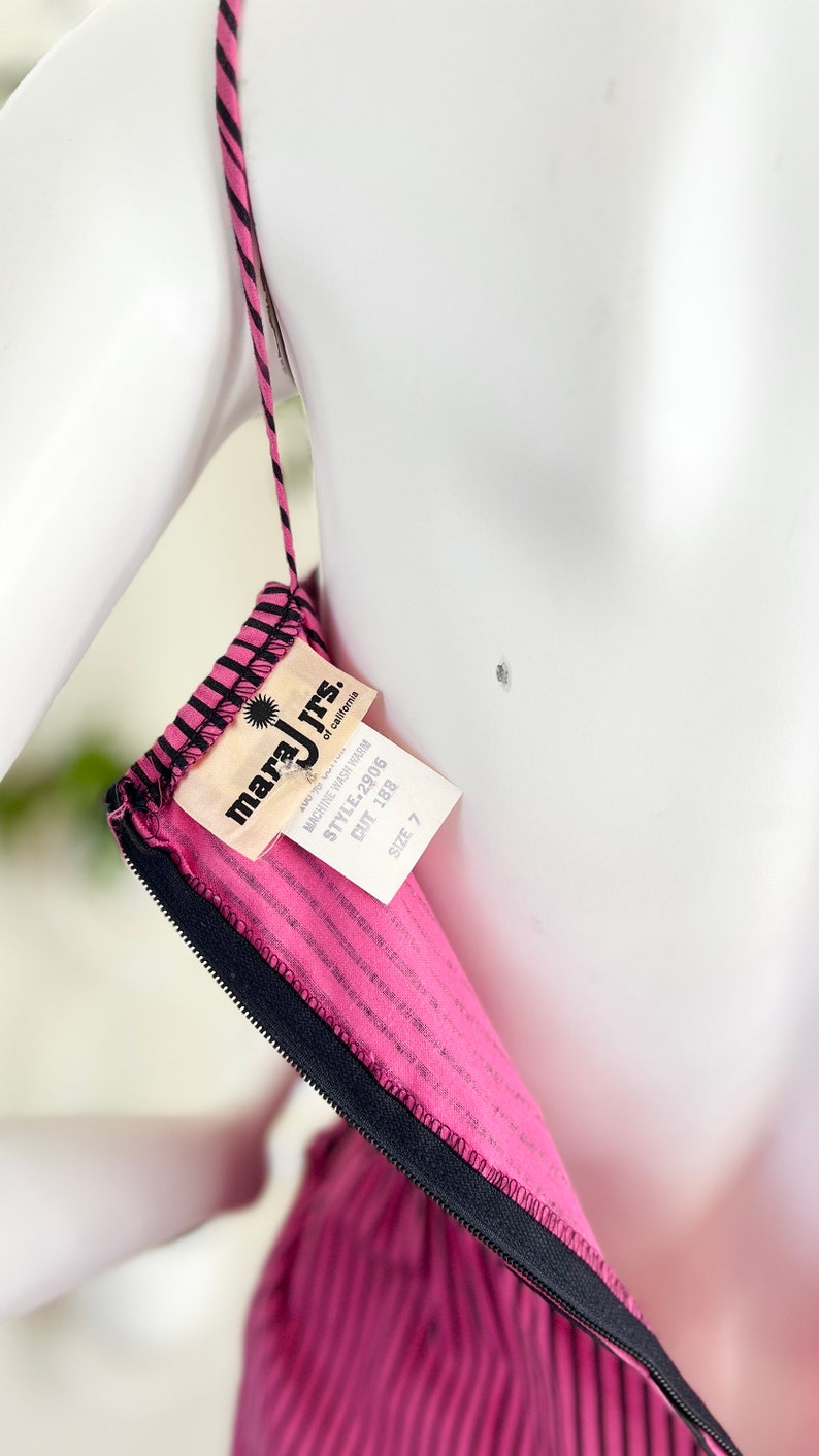 May include: Pink and black striped dress with a black zipper and a white tag that reads "mara jrs. of california" with the text "machine wash warm" and "style 2905 cut 188 size 7"