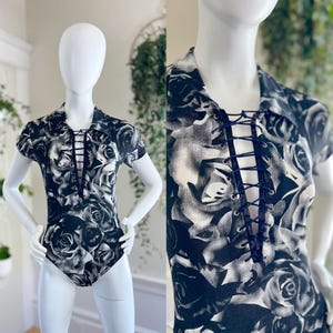 May include: Black and white bodysuit with a lace-up front and a rose print.