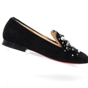 May include: Black suede loafers with a decorative embellishment of black, silver, and iridescent beads.