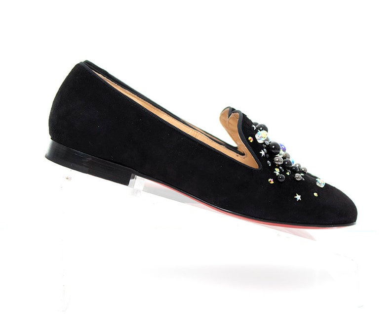 May include: Black suede loafers with a decorative embellishment of black, silver, and iridescent beads.