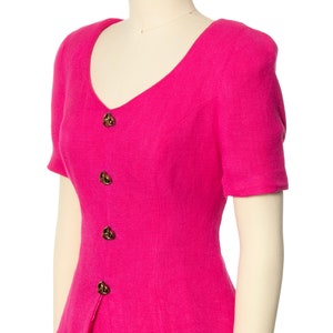 May include: A hot pink short-sleeved dress with a v-neck and button closure. The dress has a fitted bodice and a skirt that falls to the knees.