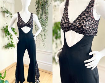 May include: Black jumpsuit with a lace top and a plunging neckline. The jumpsuit has a wide-leg silhouette and is made of a stretchy fabric.