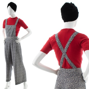 Könnte beinhalten: Ein schwarzer und weißer Blumenmuster-Jumpsuit mit einem roten, kurzärmeligen Oberteil. Der Jumpsuit hat weite Beine und ein Kreuzband-Design.