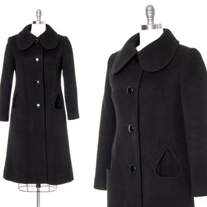May include: A black wool coat with a large, rounded collar and unique curved pockets. The coat has a button closure and a fitted silhouette.