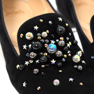 May include: Black suede loafers with a star and iridescent bead embellishment.
