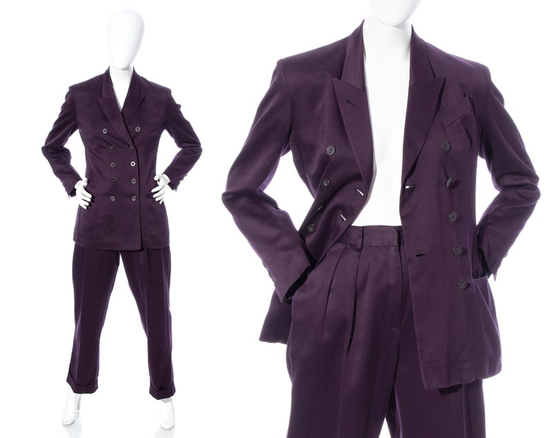 Pu&ograve; includere: Un abito doppiopetto di colore viola scuro. Il completo comprende una giacca con revers a punta e un paio di pantaloni abbinati.