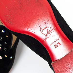 May include: Black suede loafers with a red leather sole and a star-shaped embellishment. The sole is marked "Christian Louboutin" and "Made in Italy 35 1/2".