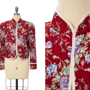 May include: A red quilted jacket with a floral print. The jacket has a mandarin collar and a white trim.