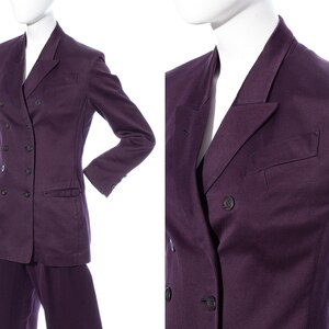 Pu&ograve; includere: Un blazer doppiopetto di colore viola scuro. Il blazer ha un colletto a revers e un solo bottone su ogni polsino. Il blazer &egrave; realizzato in un tessuto liscio e testurizzato.