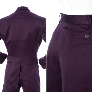 Pu&ograve; includere: Un completo viola con giacca e pantaloni. La giacca ha un solo spacco sul retro e i pantaloni hanno una tasca posteriore con bottone.